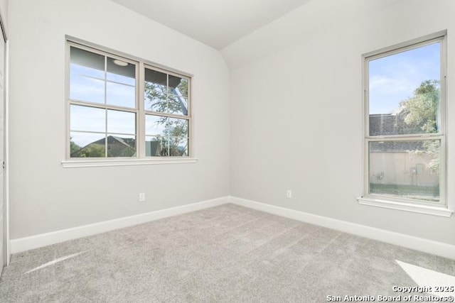 spare room featuring vaulted ceiling and light carpet