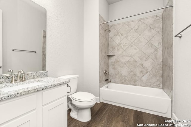 full bathroom featuring hardwood / wood-style flooring, tiled shower / bath, vanity, and toilet