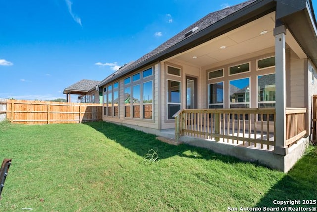 rear view of property with fence, a patio, and a yard