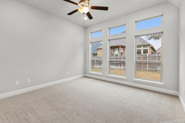 spare room with a towering ceiling, carpet flooring, a ceiling fan, and baseboards