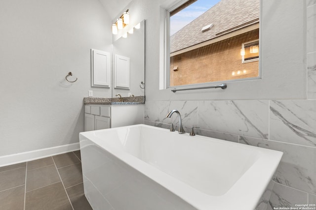 bathroom with a freestanding bath, vanity, baseboards, and tile patterned floors