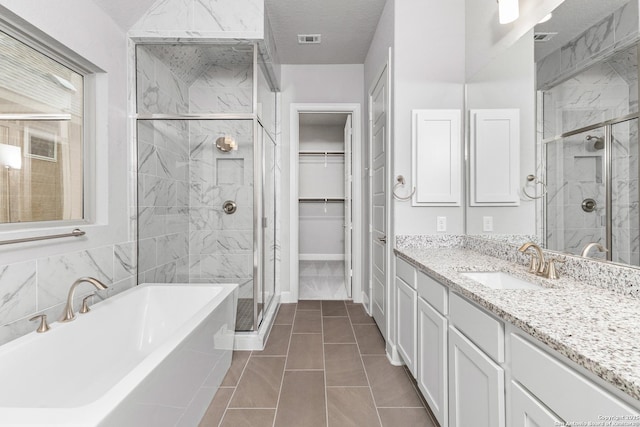 bathroom featuring a walk in closet, visible vents, a freestanding bath, a stall shower, and vanity