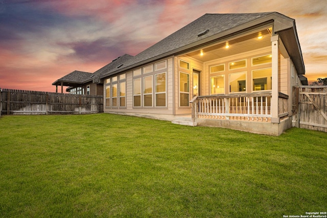 back of property with a fenced backyard and a lawn