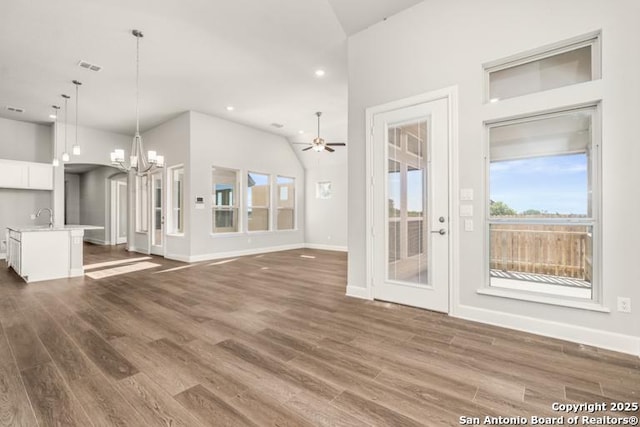 unfurnished living room with lofted ceiling, sink, ceiling fan with notable chandelier, and dark hardwood / wood-style floors