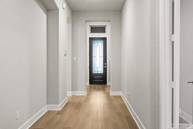 doorway to outside with light wood-type flooring and baseboards