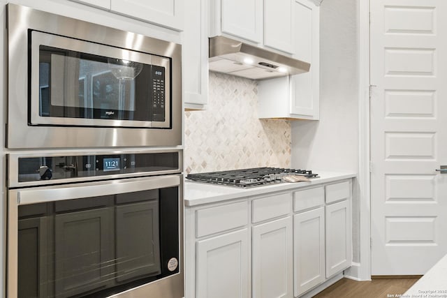 kitchen featuring hardwood / wood-style flooring, appliances with stainless steel finishes, white cabinets, and decorative backsplash