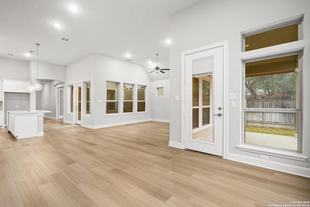 unfurnished living room featuring lofted ceiling, sink, ceiling fan, and light wood-type flooring