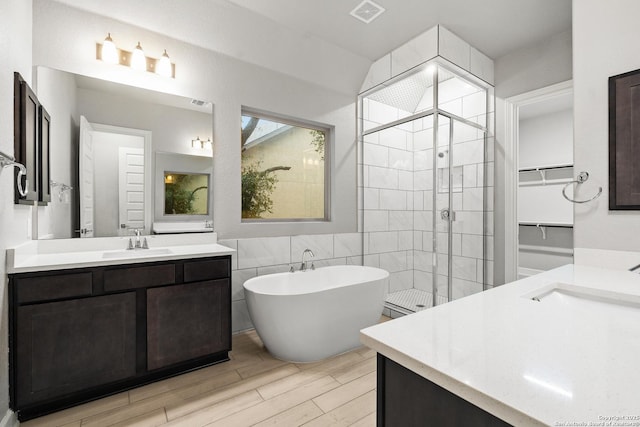 bathroom featuring tile walls, hardwood / wood-style floors, vanity, and separate shower and tub