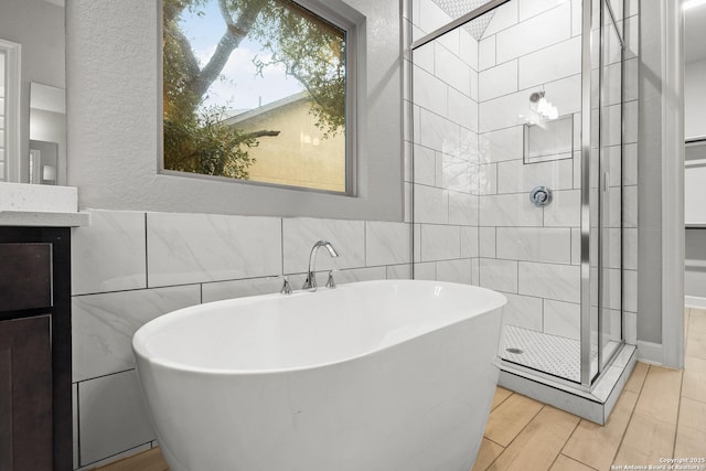 bathroom with vanity, hardwood / wood-style floors, independent shower and bath, and tile walls