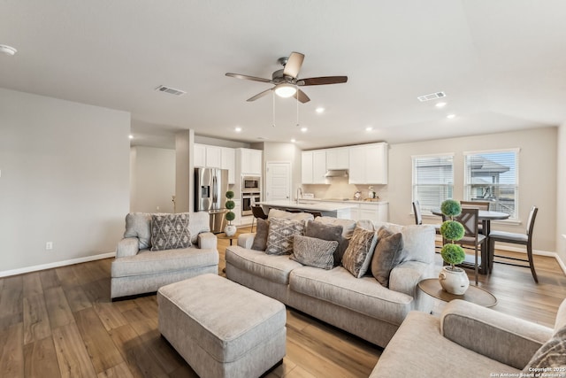 living room with sink, light hardwood / wood-style flooring, and ceiling fan