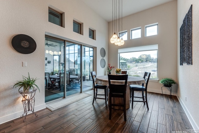 dining space featuring an inviting chandelier, a towering ceiling, and dark hardwood / wood-style flooring