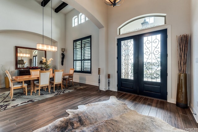 foyer entrance with plenty of natural light, a notable chandelier, dark hardwood / wood-style flooring, and french doors