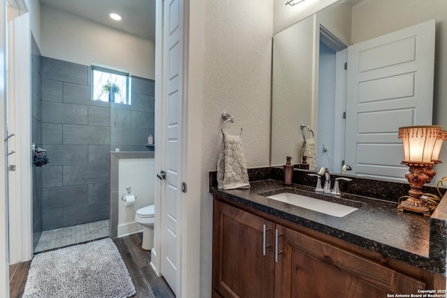 bathroom with vanity, tiled shower, and toilet