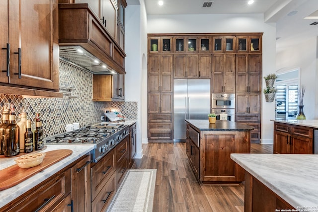 kitchen with backsplash, a center island, stainless steel appliances, dark wood-type flooring, and custom range hood