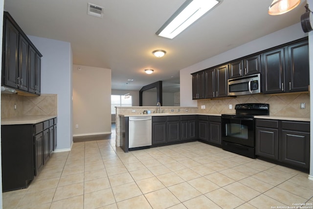 kitchen featuring sink, backsplash, stainless steel appliances, light tile patterned flooring, and kitchen peninsula