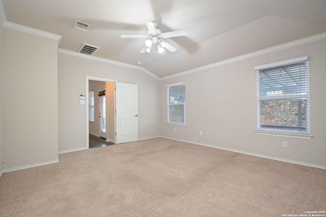 carpeted empty room featuring ornamental molding, vaulted ceiling, and ceiling fan