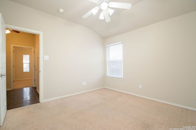 carpeted spare room with ceiling fan, vaulted ceiling, and a healthy amount of sunlight