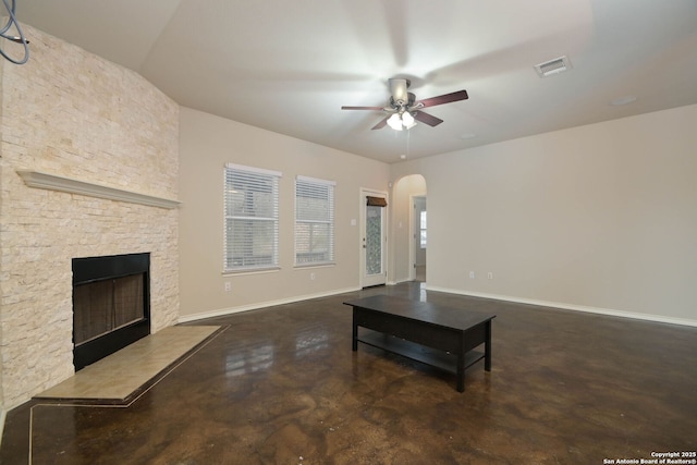 living room with a stone fireplace and ceiling fan