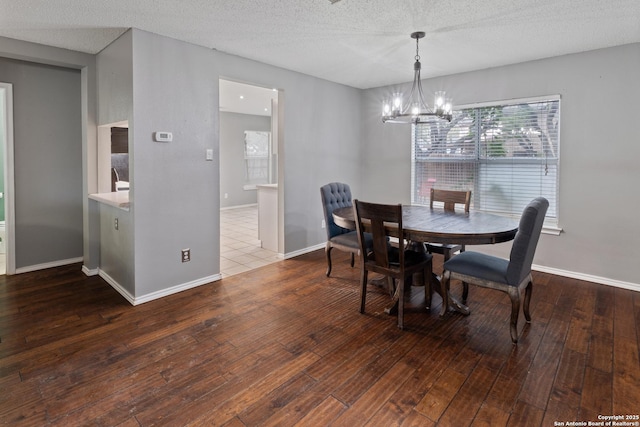 dining room with hardwood / wood-style flooring, a textured ceiling, and a notable chandelier