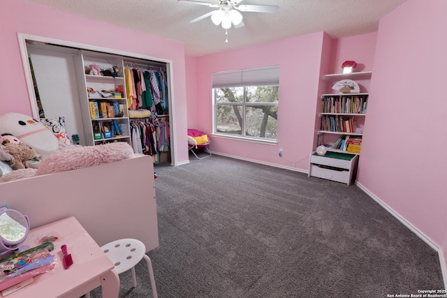 bedroom featuring ceiling fan, dark carpet, a closet, and a textured ceiling