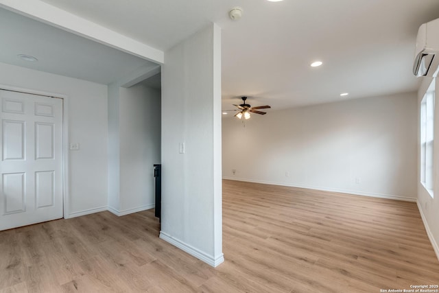 empty room featuring ceiling fan, a wall mounted AC, and light hardwood / wood-style floors