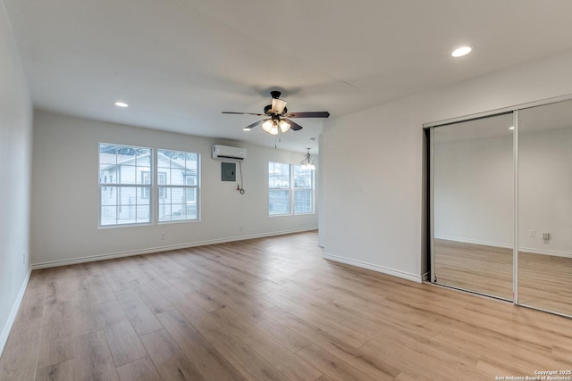 interior space with a closet, a wall mounted AC, ceiling fan, and light hardwood / wood-style flooring