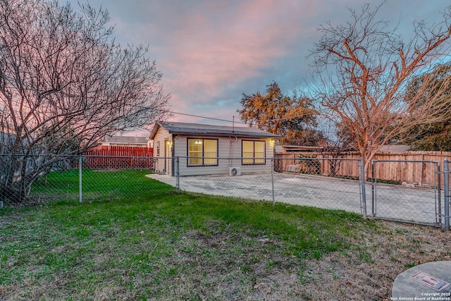 back house at dusk featuring a lawn and a patio