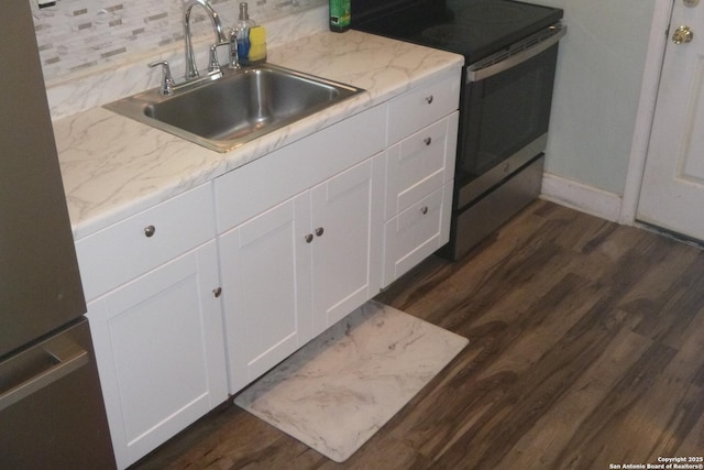 kitchen featuring sink, stainless steel range with electric cooktop, dark hardwood / wood-style floors, light stone countertops, and white cabinets