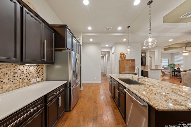 kitchen featuring sink, tasteful backsplash, decorative light fixtures, stainless steel appliances, and a large island