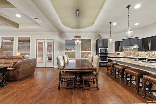 dining space featuring a raised ceiling, dark hardwood / wood-style floors, and sink