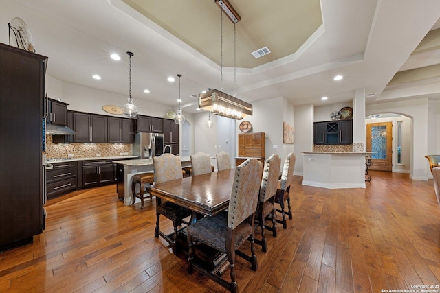 dining area featuring wood-type flooring and a tray ceiling