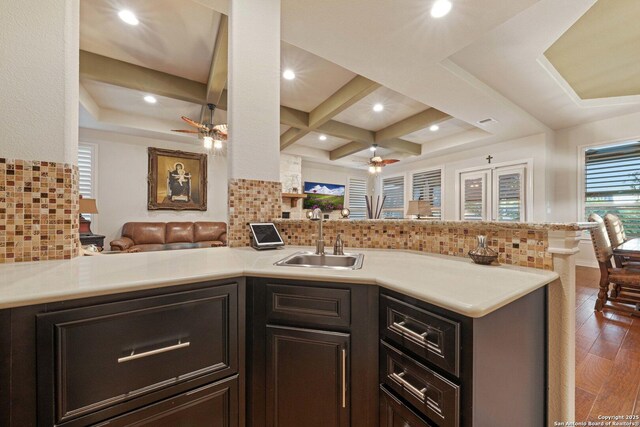 kitchen featuring sink, decorative backsplash, coffered ceiling, ceiling fan, and kitchen peninsula