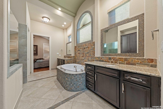 bathroom featuring a relaxing tiled tub, vanity, and tile patterned floors