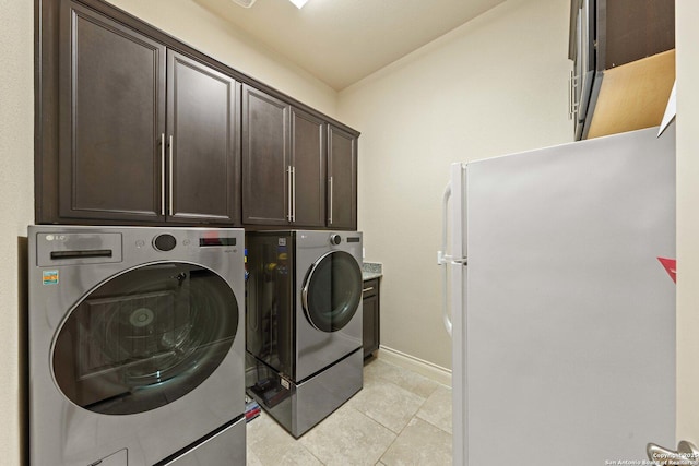 clothes washing area featuring cabinets, separate washer and dryer, and light tile patterned floors