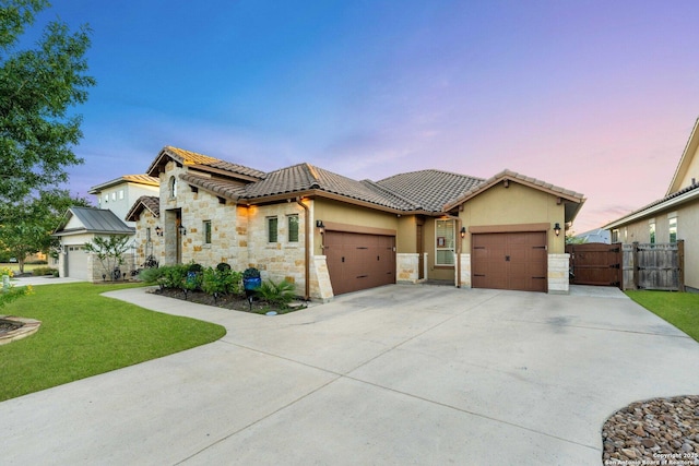 mediterranean / spanish home with a garage and a lawn