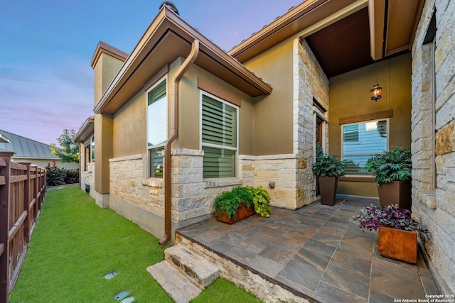 property exterior at dusk featuring a patio and a lawn