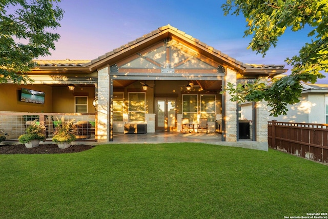 back of property with ceiling fan, a yard, and a patio area