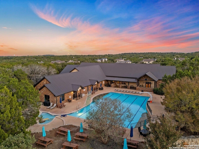 pool at dusk with a patio area