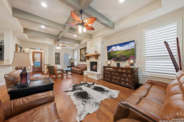 living room featuring coffered ceiling, beam ceiling, ceiling fan, a fireplace, and hardwood / wood-style floors