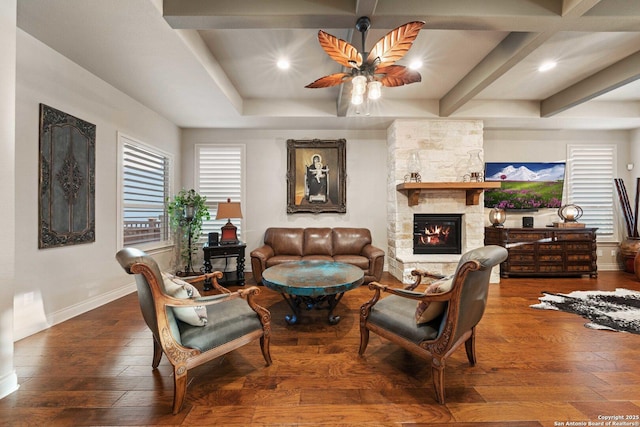 living room featuring dark hardwood / wood-style flooring, a fireplace, beamed ceiling, and ceiling fan