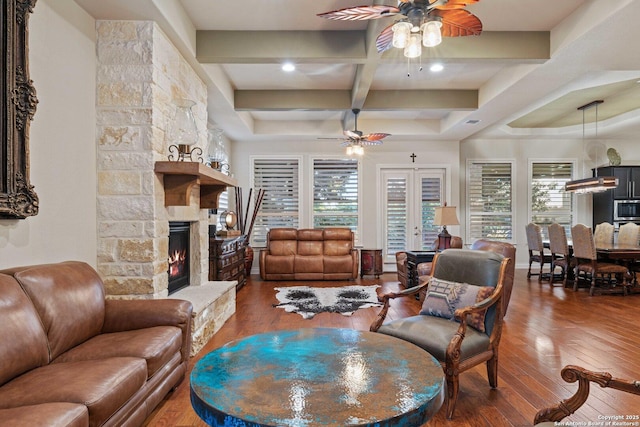 living room with hardwood / wood-style flooring, plenty of natural light, a stone fireplace, and ceiling fan