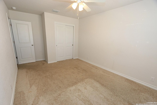 unfurnished bedroom featuring ceiling fan, a closet, and light carpet