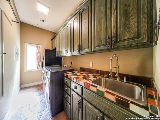 kitchen with vaulted ceiling, sink, washing machine and clothes dryer, and dark brown cabinetry