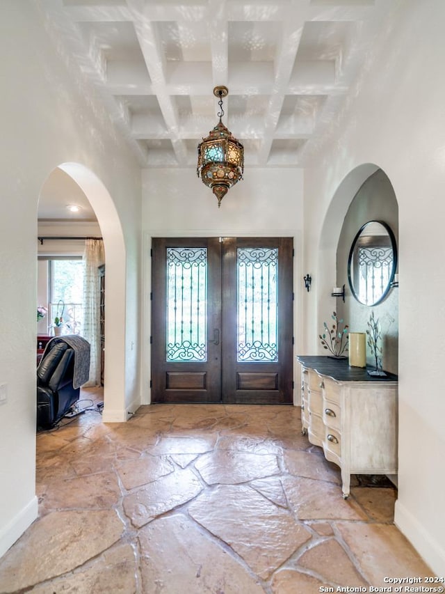 foyer entrance featuring coffered ceiling, a towering ceiling, and beam ceiling