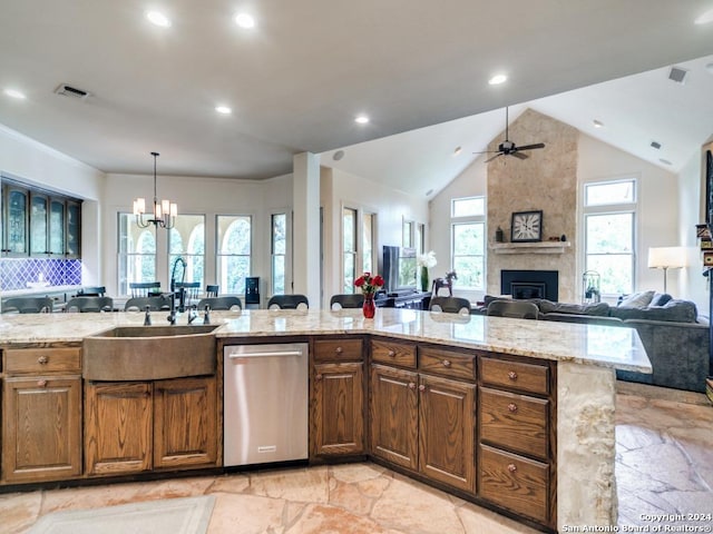 kitchen with light stone counters, sink, decorative light fixtures, and a large fireplace