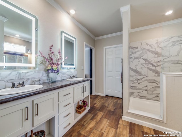 bathroom with hardwood / wood-style flooring, ornamental molding, vanity, and a tile shower