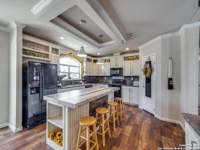 kitchen featuring sink, a raised ceiling, a kitchen island, pendant lighting, and black appliances