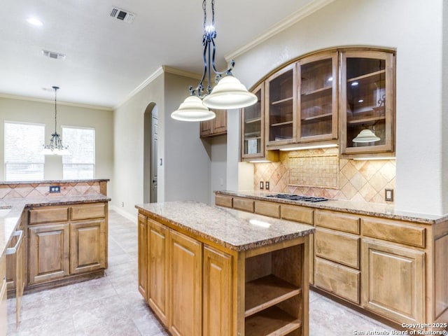 kitchen with tasteful backsplash, ornamental molding, light stone countertops, a kitchen island, and decorative light fixtures