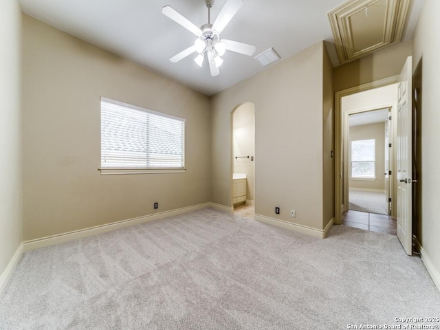 unfurnished bedroom with ceiling fan, connected bathroom, and light carpet