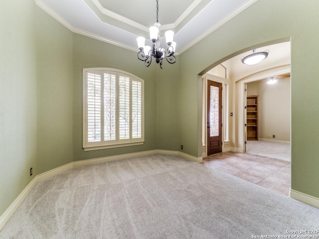 empty room with a raised ceiling, crown molding, light colored carpet, and an inviting chandelier